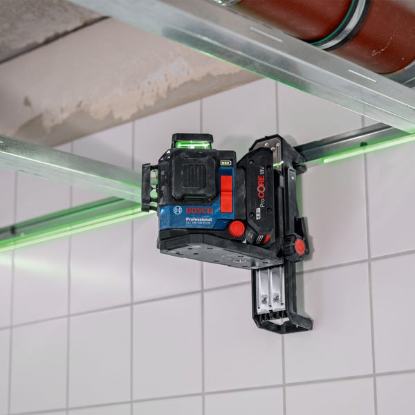 Bosch Professional Linienlaser mit grünen Laserlinien, montiert an einer Wandhalterung zur Ausrichtung von Metallprofilen an einer Fliesenwand.