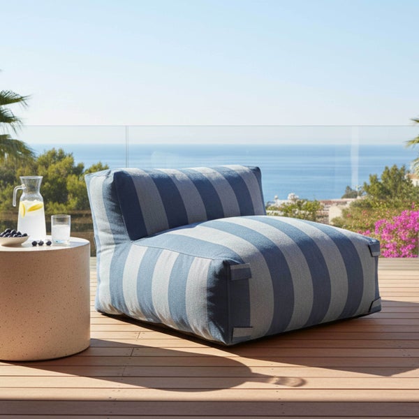 Gestreifter Outdoor-Sessel auf einer Holzterrasse mit Meerblick und Beistelltisch.