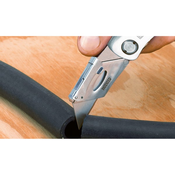 Eine Person schneidet einen Schlauch mit einem Klappmesser.