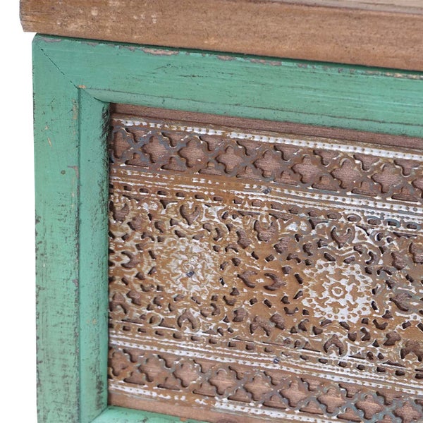 Detailansicht eines Holzmöbels mit Ornamenten und einem grünen Rahmen