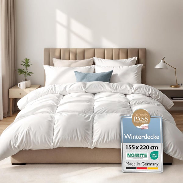 Weiße Winterdecke 155 mal 220 Zentimeter auf einem beigen Polsterbett in einem hellen, modern eingerichteten Schlafzimmer.