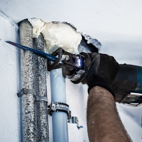 Handwerker sägt Rohr mit einer Säbelsäge