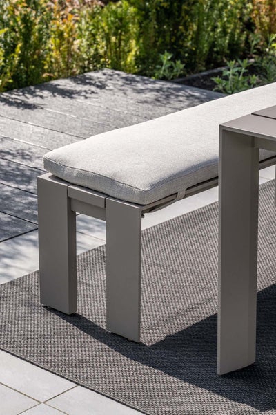 Moderne Gartenbank aus Aluminium mit Sitzpolster auf einer Terrasse mit Outdoor-Teppich.