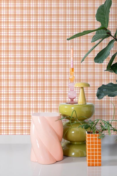 Szene mit karierter Tapete, Beistelltisch, Kerzenständer und Zimmerpflanze.
