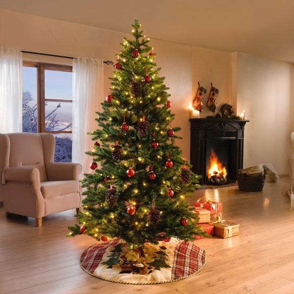 Festlich geschmückter Weihnachtsbaum mit Beleuchtung, Christbaumkugeln, Tannenzapfen und Geschenken in einem gemütlichen Wohnzimmer