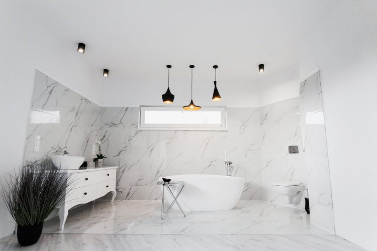 Helles Badezimmer mit freistehender Badewanne, Waschtisch und Marmorfliesen