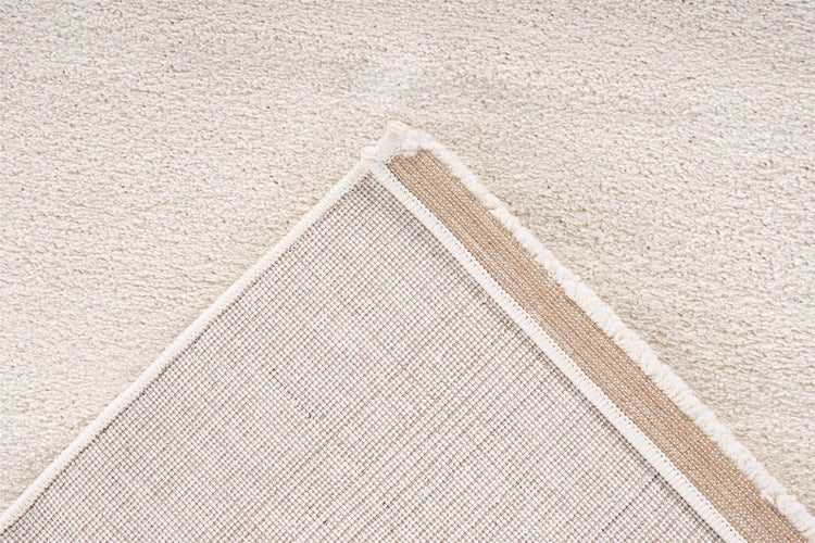 Detailansicht eines Teppichs mit weichem Flor und der strukturierten Rückseite mit verstärkter Kante.