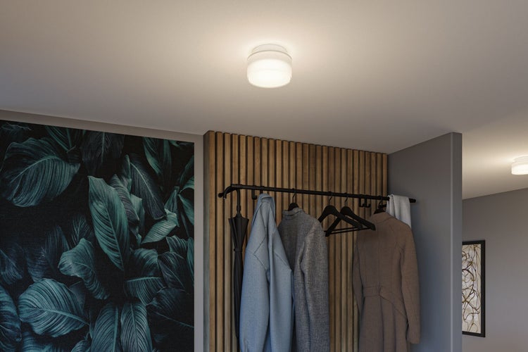 Moderne Deckenleuchte in einem Flur mit Holzlamellenwand, einer Garderobe mit Jacken und einer großflächigen Tapete mit Blattmuster.