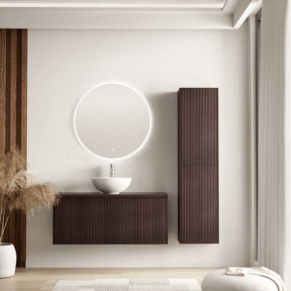 Modernes Badezimmer mit Waschtisch, hängendem Waschbeckenunterschrank, beleuchtetem Rundspiegel und hohem Seitenschrank in dunkler Riffeloptik.