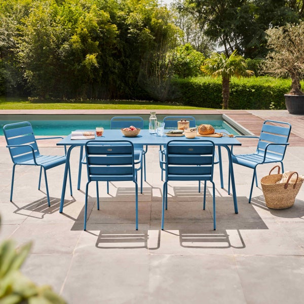Blaues Garten-Essset aus Metall mit rechteckigem Tisch und sechs Stühlen auf einer Steinterrasse am Pool im Garten.