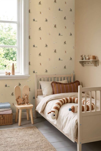 Kinderzimmer mit Tapete mit Tier und Fahrrad Motiven, helles Holzbett, Stuhl mit Hasenohren und Dekoration, freundliche Atmosphäre.