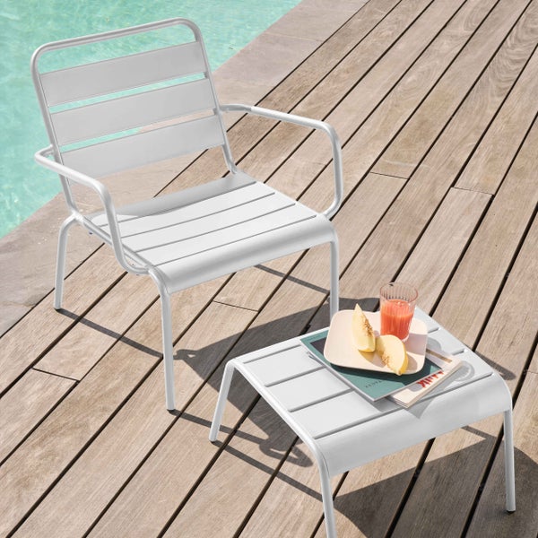 Moderner Loungesessel und Beistelltisch aus Aluminium mit Lamellen auf einer Holzterrasse am Pool.