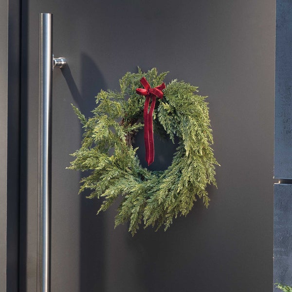 Weihnachtskranz aus künstlichen Tannenzweigen mit Schleife zur Dekoration an einer Haustür.
