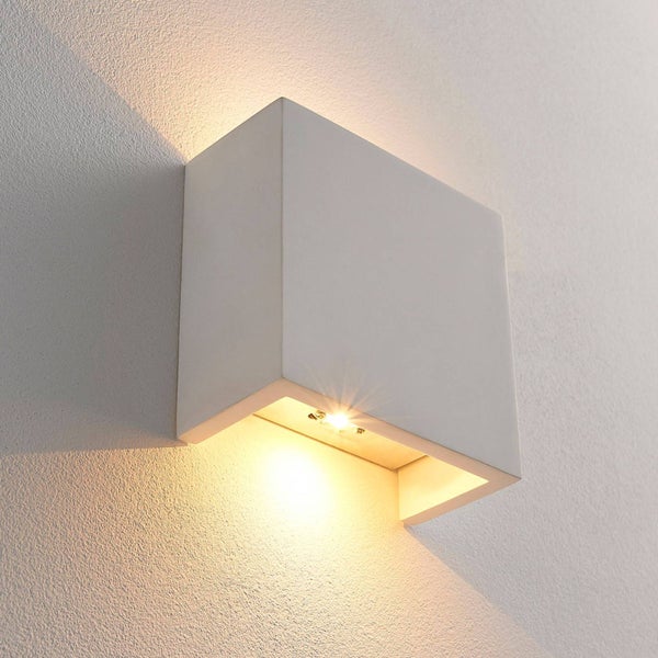 Moderne weiße Wandleuchte in rechteckiger Form mit Lichtaustritt nach oben und unten an einer strukturierten Wand.