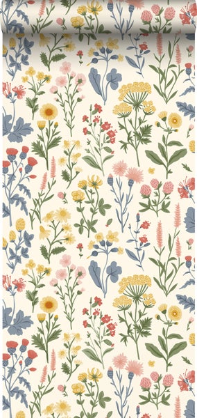 Vliestapete mit buntem Wiesenblumen-Muster hinter einer rustikalen Holzbank mit Kissen, Decke und Gießkanne.