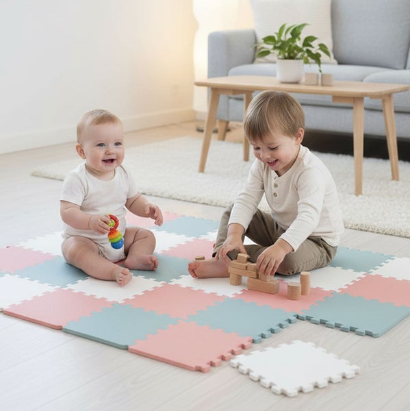 Zwei Kinder sitzen auf einer quadratischen Spielmatte aus ineinandergreifenden Puzzleteilen im Wohnzimmer und spielen.