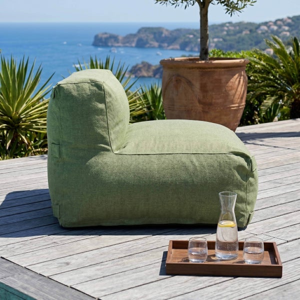 Grüner Outdoor-Sitzsack auf einer Holzterrasse mit Meerblick und einem Tablett mit Getränken.