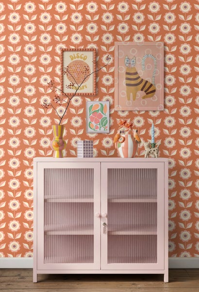 Modernes Zimmer mit Retro-Tapete, rosa Vitrine mit geriffelten Glastüren, bunter Wandkunst und Dekoration.