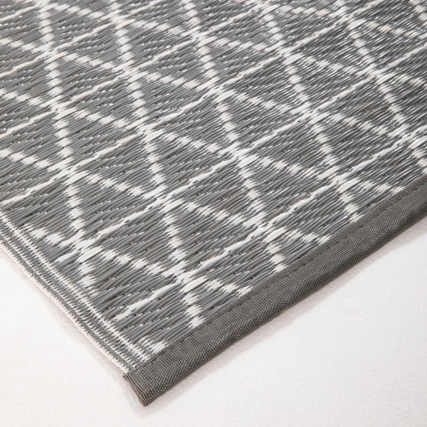 Outdoorteppich mit geometrischem Rautenmuster in Grau und Weiß, gewebtes Kunststoffmaterial mit eingefasstem Rand.