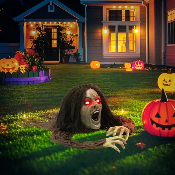 Halloween-Szene mit einem Zombie, der aus dem Rasen kriecht, roten Augen und Kürbislaternen im Garten eines Hauses.
