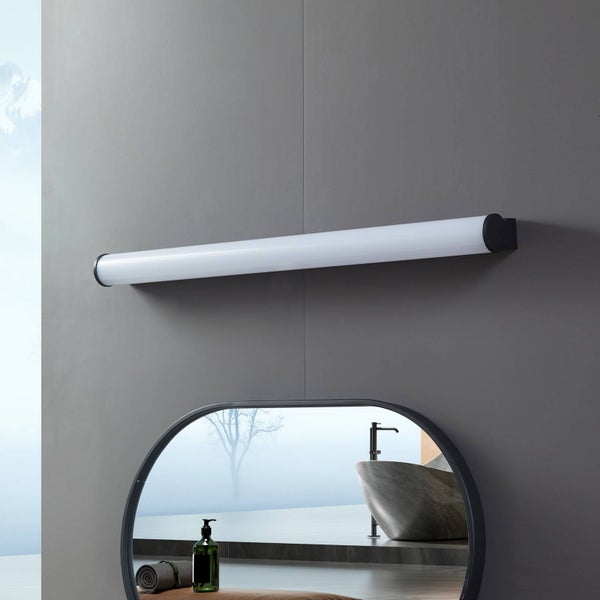 Moderne zylindrische LED-Spiegelleuchte mit schwarzen Endkappen über einem ovalen Spiegel in einem minimalistischen Badezimmer.