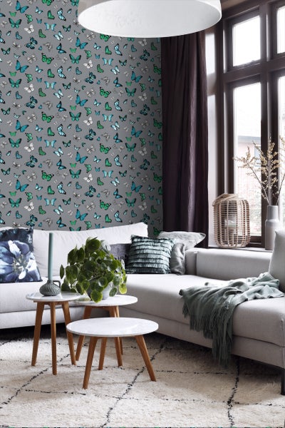 Wohnzimmer mit Sofa, Couchtisch und Tapete mit Schmetterlingsmuster.