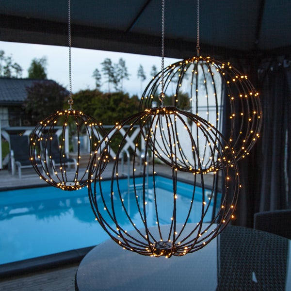 Drei runde LED-Hängeleuchten mit Metallrahmen und Lichtern auf einer Terrasse mit Pool