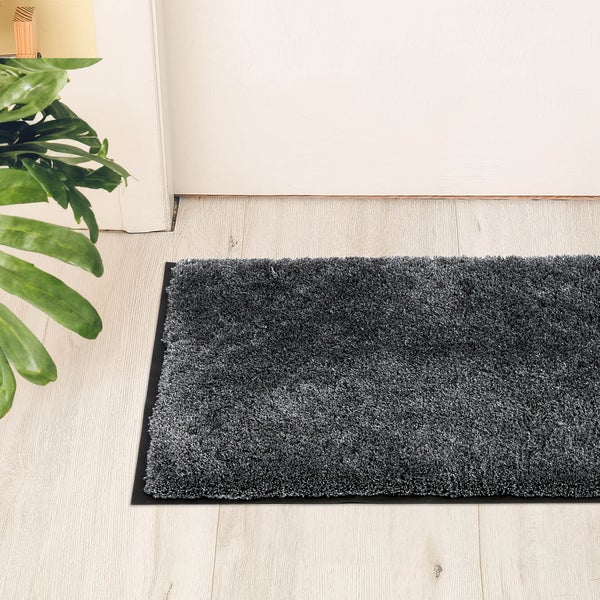Grauer Shaggy Teppich vor einer Tür auf einem Holzboden