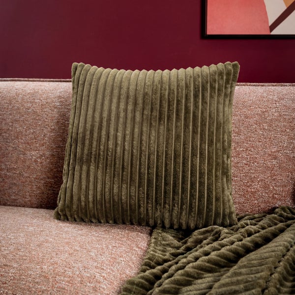 Dekoratives Cordkissen auf einem Sofa mit passender Decke