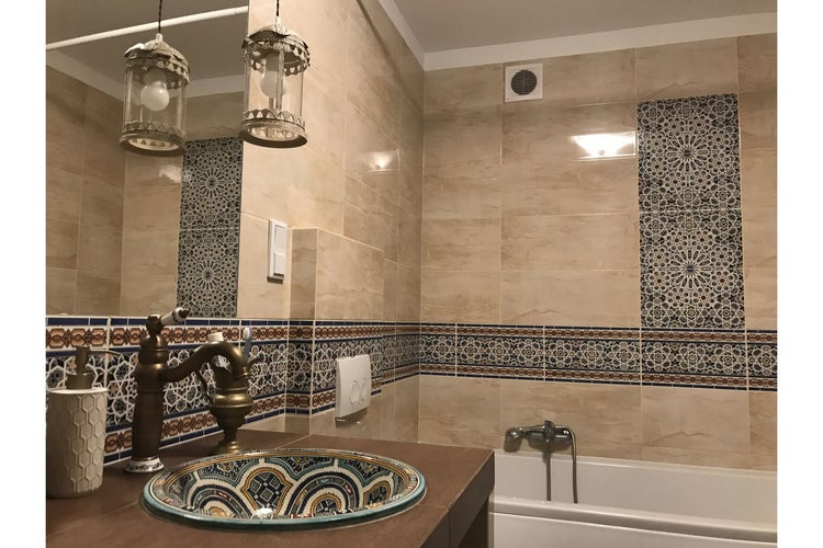 Badezimmer mit Waschbecken, Badewanne, Fliesen und Beleuchtung im orientalischen Stil