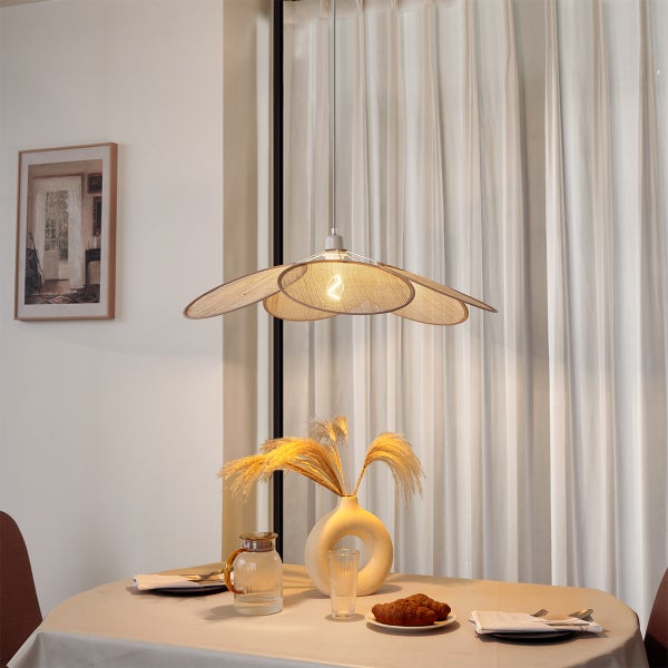 Pendelleuchte mit blütenblattförmigen Schirmen aus Geflecht über einem Esstisch mit Vase und Gebäck in einer hellen, organisierten Umgebung.