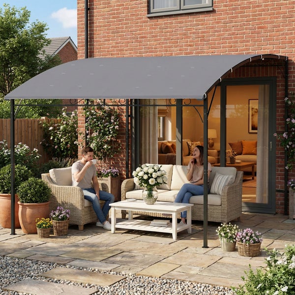 Graue Terrassenüberdachung an einem Backsteinhaus mit Gartenmöbeln aus Geflecht, Couchtisch und blühenden Pflanzen auf einer gepflasterten Terrasse.