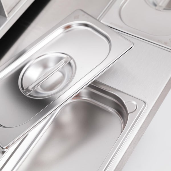 Olivenbaum Olea europaea mit knorrigem Stamm in einem großen schwarzen Pflanzkübel im Freien.