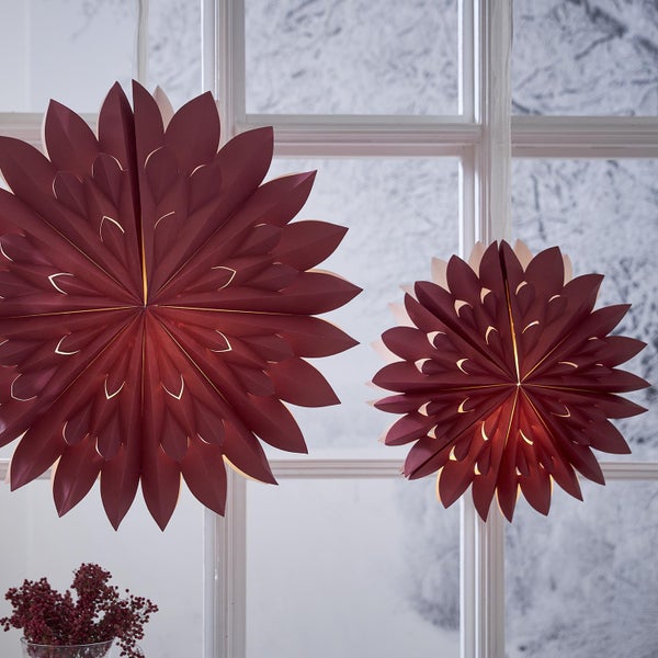 Zwei Papiersterne hängen vor einem Fenster und sorgen für eine festliche Beleuchtung.