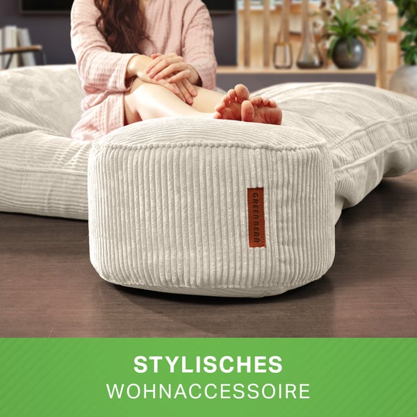 Frau sitzt auf Sitzsack mit Hocker im Wohnzimmer