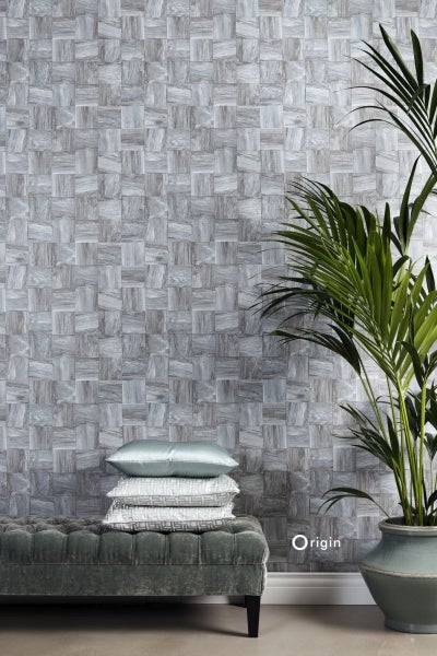 Wand mit grauer Mosaik-Optik, Bank, Kissen und Zimmerpflanze