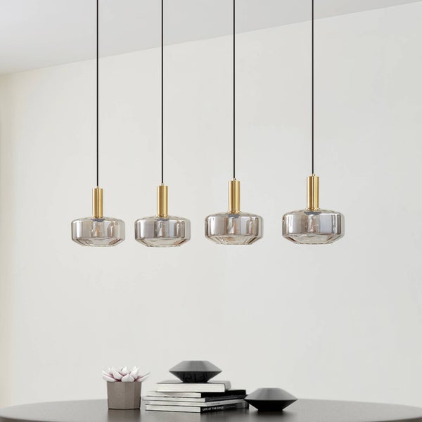 Moderne 4-flammige Pendelleuchte mit rauchfarbenen Glasschirmen und messingfarbenen Details über einem Tisch.