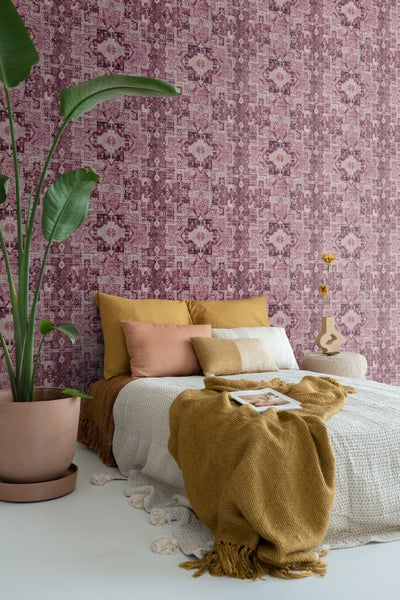 Schlafzimmer mit gemusterter Tapete, Bett und Zimmerpflanze