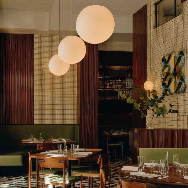 Innenraum eines Restaurants mit Tischen, Stühlen und runden Hängelampen