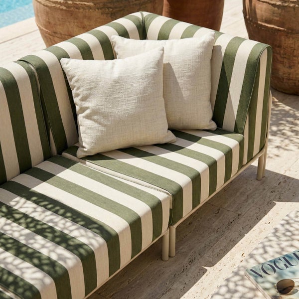 Gestreiftes Gartensofa-Modul in Grün und Weiß mit zwei Dekokissen auf einer Terrasse im Außenbereich.