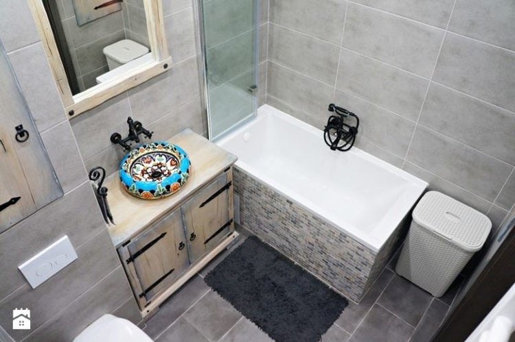 Badezimmer mit Badewanne, Waschbeckenunterschrank mit Aufsatzwaschbecken und Spiegel