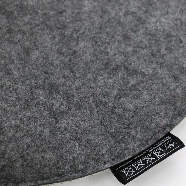 Graues Sitzkissen aus Filz mit Pflegeetikett: Nur Handwäsche, nicht bleichen, nicht im Trockner trocknen, nicht bügeln, nicht chemisch reinigen.