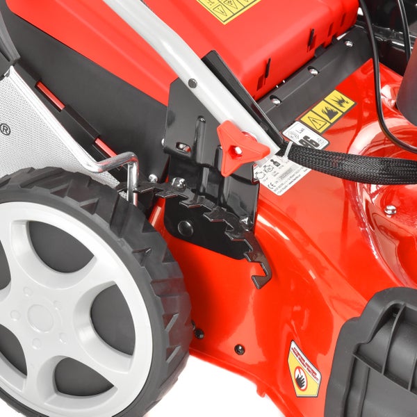 Detailansicht eines roten Rasenmähers mit Rad und rotem Hebel zur mehrstufigen zentralen Schnitthöhenverstellung.