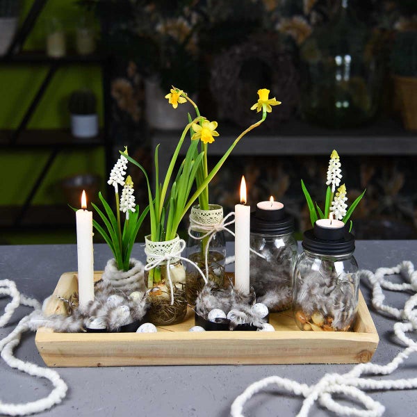 Dekorationstablett mit Blumen, Kerzen und Federn in Gläsern