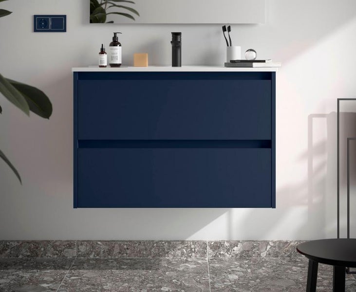 Moderner, dunkelblauer wandhängender Waschbeckenunterschrank mit zwei Schubladen und weißer Waschtischplatte in einem Badezimmer.