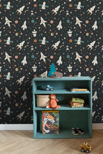 Dunkle Weltraumtapete mit Raketen, Planeten und Sternen in einem Kinderzimmer hinter einem Regal mit Spielzeug und Büchern auf Holzboden.