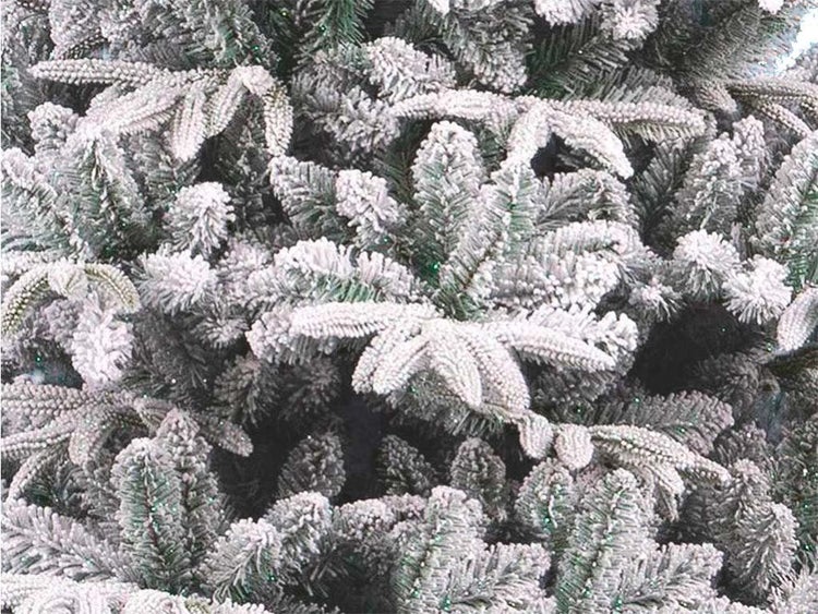 Detailansicht der Zweige eines künstlichen Weihnachtsbaums mit künstlicher Schnee-Beschichtung für eine winterliche Optik.
