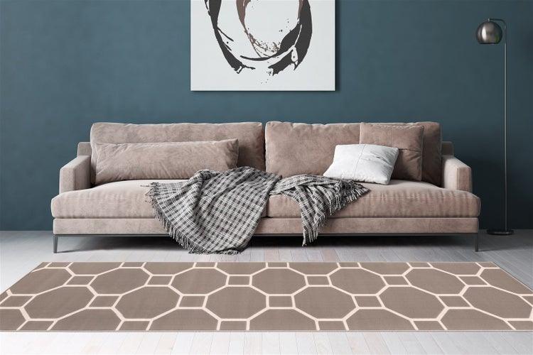 Wohnzimmer mit modernem Sofa, karierter Decke und rechteckigem Teppich mit geometrischem Sechseckmuster auf Holzboden.