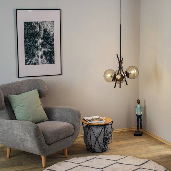 Wohnzimmer mit Sessel, Beistelltisch, Pendelleuchte und Dekorationsartikeln für eine gemütliche Atmosphäre