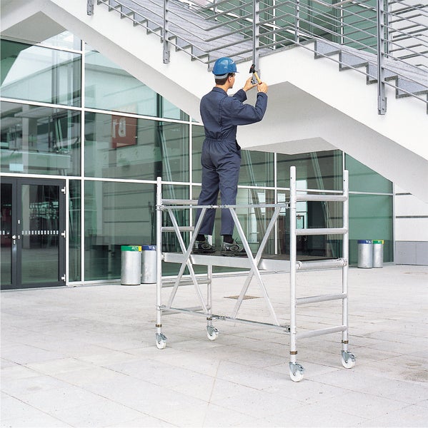 Eine Person arbeitet auf einem Fahrgerüst an einem Gebäude.